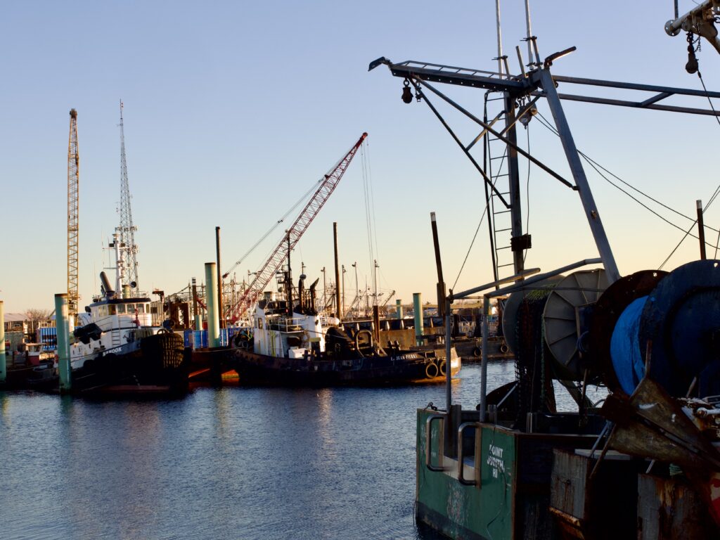 Fishing boats and cranes at marina dock at sunset